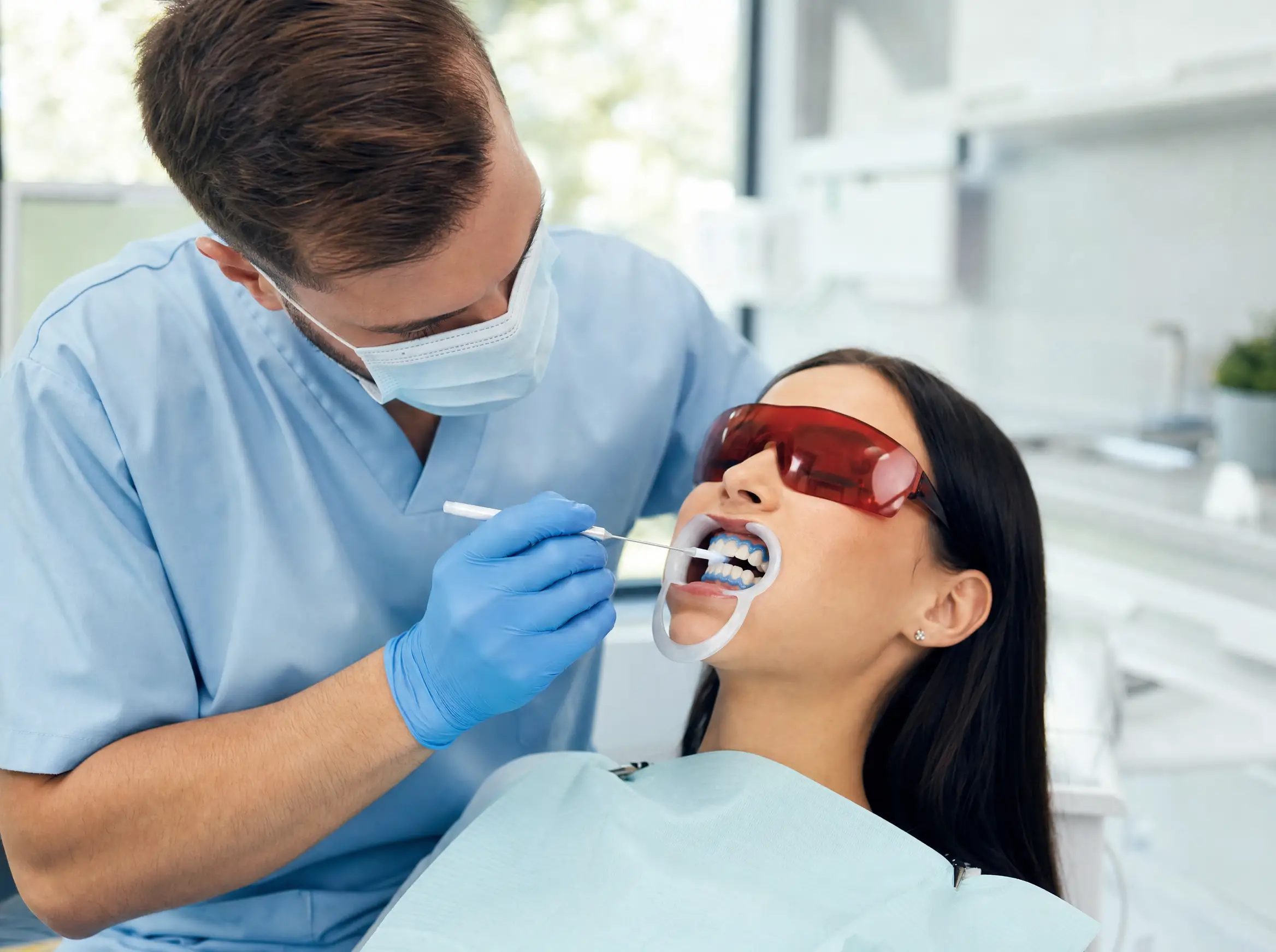 Zahnärztin führt ein professionelles In-Office-Bleaching bei einer Patientin durch